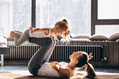 Mother and daughter practice a yoga pose together.